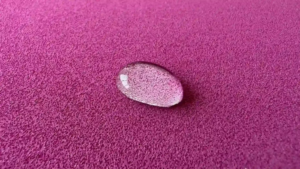 Close-up of a clear water droplet sitting on a vibrant purple, textured EVA foam sheet, highlighting the material's waterproof and non-absorbent closed-cell structure.