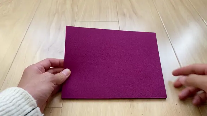 Durable and flexible EVA foam sheet in purple being handled to show material thickness and pliability for DIY crafts and cosplay.